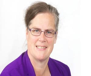 Janet Withell, a woman with glasses and brown hair pulled back, wearing a purple blazer, smiles at the camera against a plain white background—representing Utility Warehouse Discount Club.
