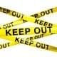 A yellow caution tape with the words keep out, warning of potential hazards.