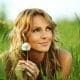 A woman enjoying a moment of work-life balance as she reclines in the grass, toying with a delicate dandelion.
