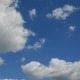 A serene blue sky with fluffy white clouds.