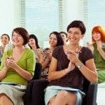iStock_000019321212XSmall A group of working women sitting in chairs and clapping.