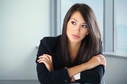 A career-oriented woman in a business suit leaning against a desk, showcasing work-life balance while confidently handling her job.