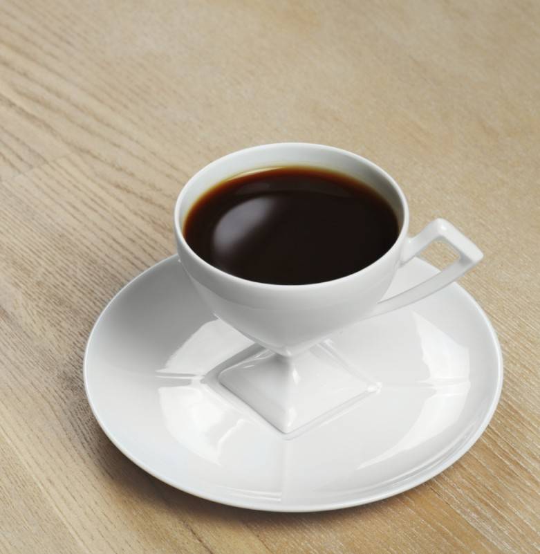 A cup of coffee on a saucer on a wooden table, perfect for women returners seeking work-life balance.