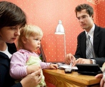 A man and woman, career-oriented professionals, working at a desk with a child.