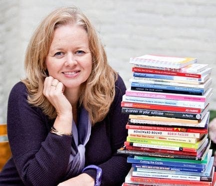 A working mother sitting at a table with a stack of books.