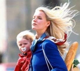 A career-driven woman carrying a baby in a blue jacket.