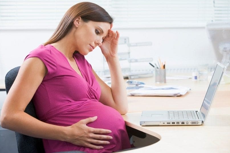 A working mum sitting at a desk with a laptop.