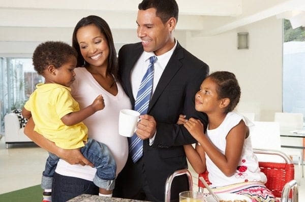 A career-focused mum finding work-life balance with her family in a living room, where the baby peacefully rests in a stroller.