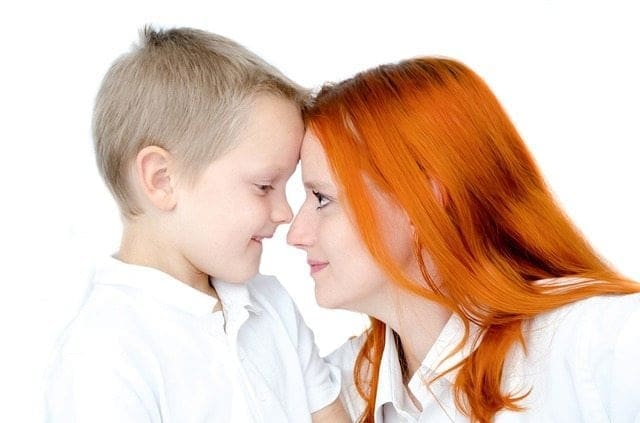 A woman with red hair and a boy with white hair working together.
