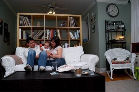 A family relaxes on a white couch in a living room, enjoying their quality time together.