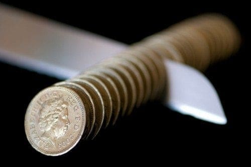 A knife is carefully balanced on top of a stack of coins.