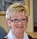 A working woman in glasses is smiling in an office.
