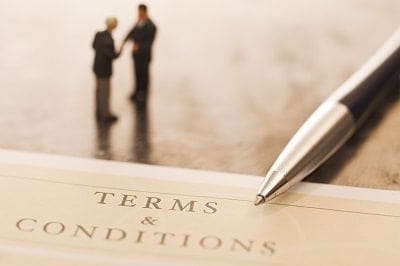 A businessman is holding a pen on top of a document that says terms and conditions related to his career job.