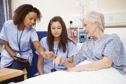 Three nurses working in a hospital bed.