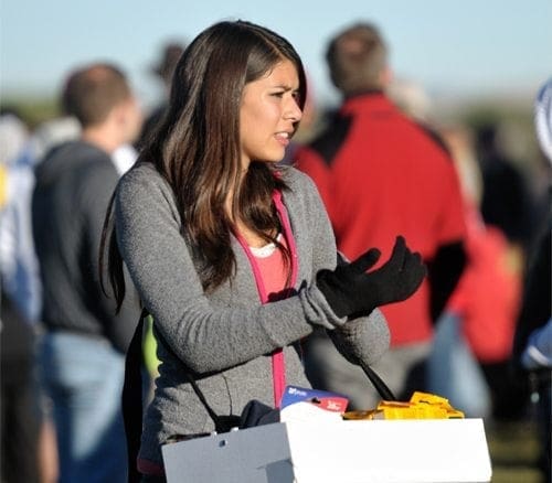 A working woman holding a box in front of a crowd, indicating her career in various jobs.