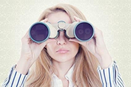 A young woman searching for career opportunities through binoculars.