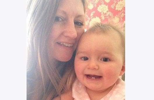 A working woman is holding a baby in her arms, exemplifying work-life balance.