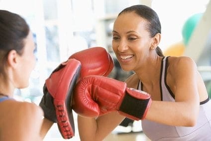 Two women in boxing gloves balancing their work-life return to the gym.