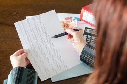 A working woman skillfully juggling her career while diligently writing on paper with a pen and using a calculator.