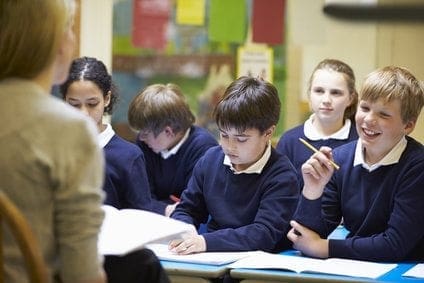 A group of children working at a desk in a classroom.