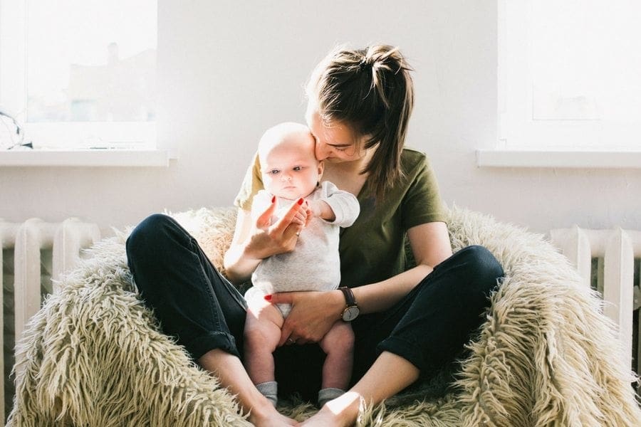 A working woman, balancing her career with her role as a mother, is pictured sitting on a fluffy chair holding her baby.