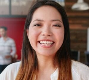 A smiling asian woman in an office, showcasing work-life balance and career success.