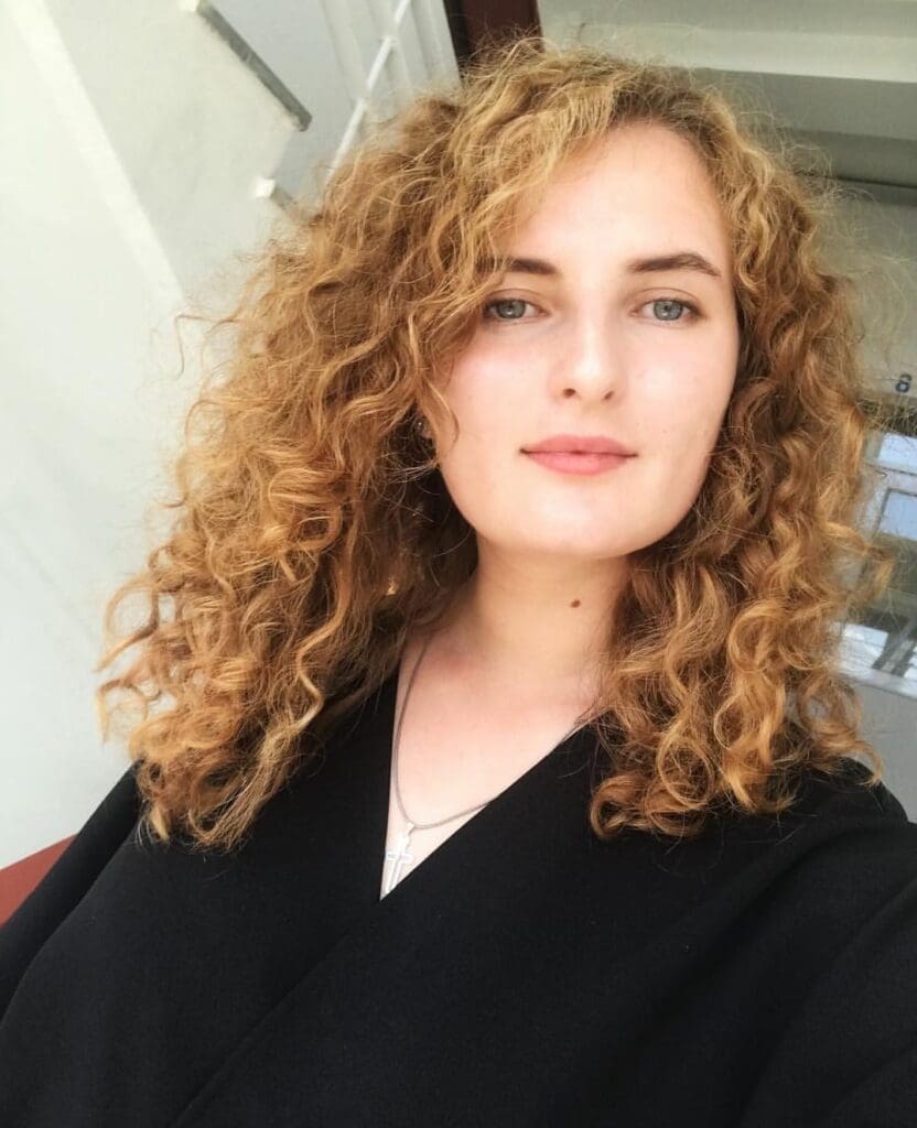 A mum with curly hair is posing for a photo.