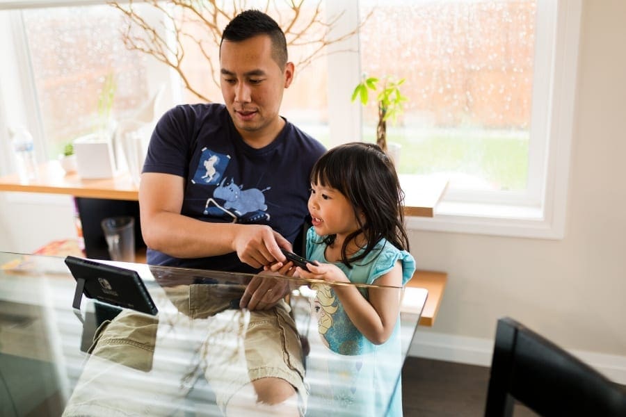 A mum and a little girl playing with a tablet, showcasing work-life balance for women returners.