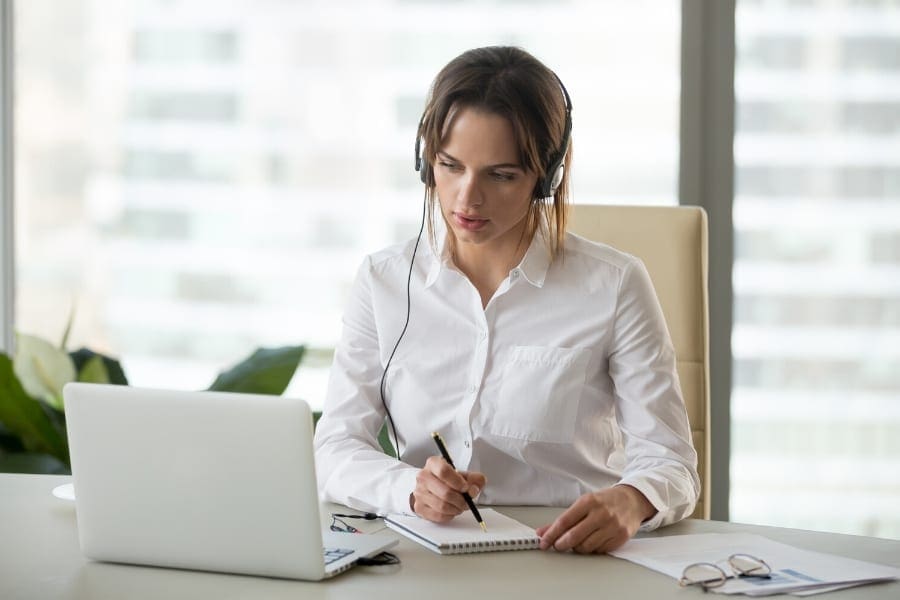 A working mother at a desk with a laptop and headphones, emphasizing work-life balance.