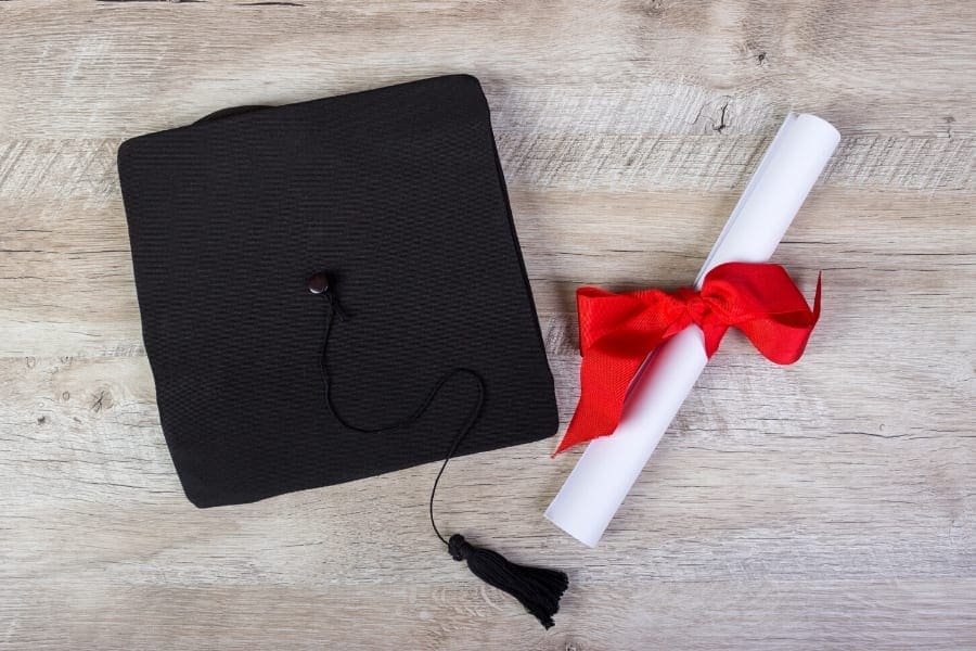 A graduation cap and diploma rest gracefully on a wooden table.