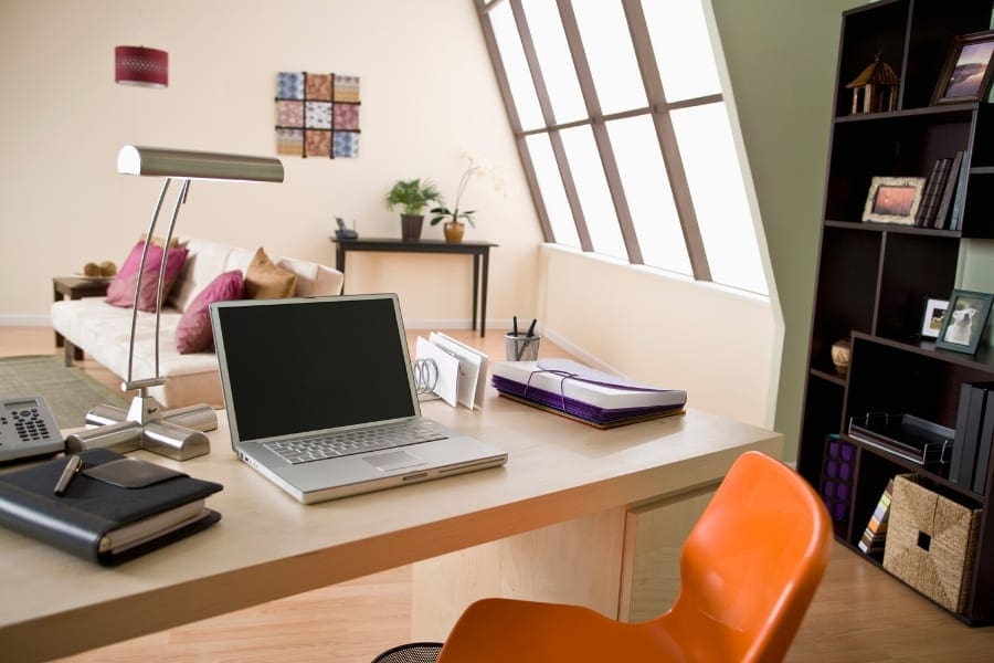 A home office with an orange chair and a laptop, providing an ideal work-life balance for career-oriented individuals or busy moms.