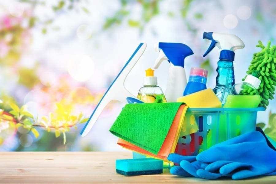 Cleaning supplies arranged in a basket on a wooden table, showcasing an organized work area.