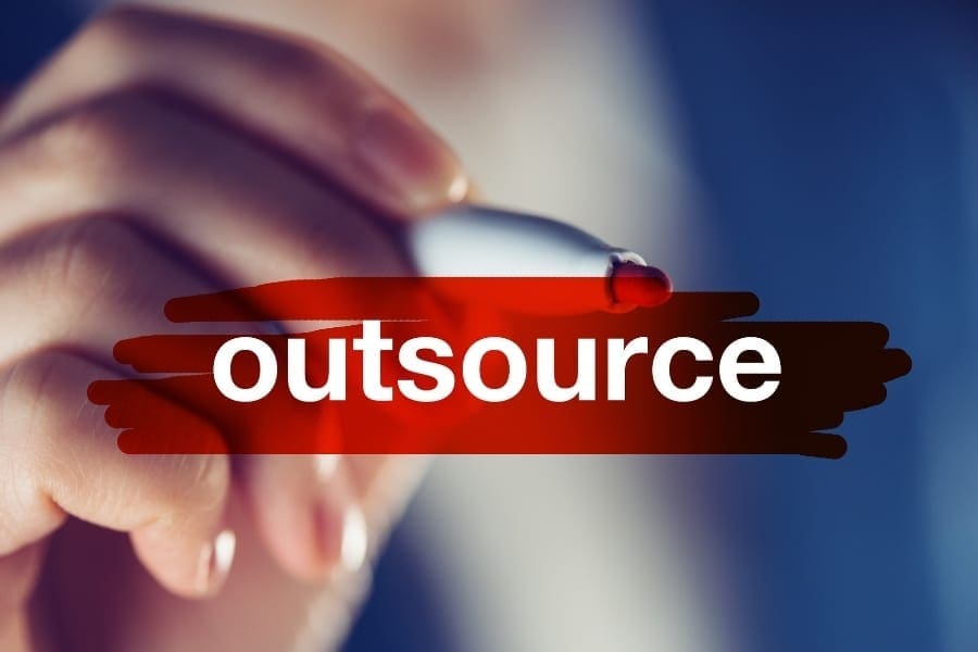 A person working on their career, writing the word outsourcing.