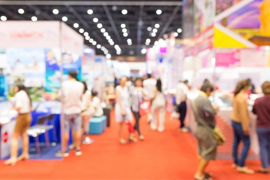 A blurry image of people working at a trade show, showcasing a glimpse into their work-life balance.