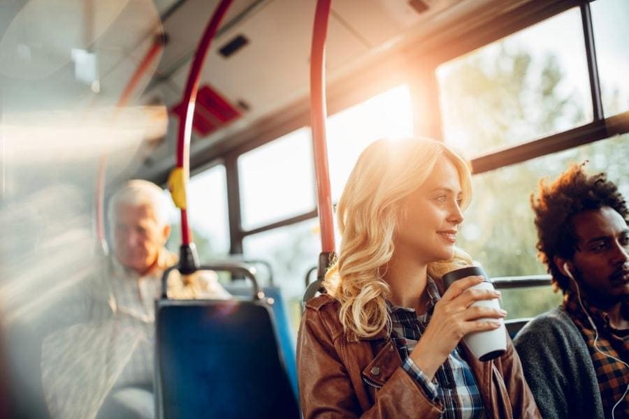 A working woman and mum sitting on a bus with a cup of coffee.