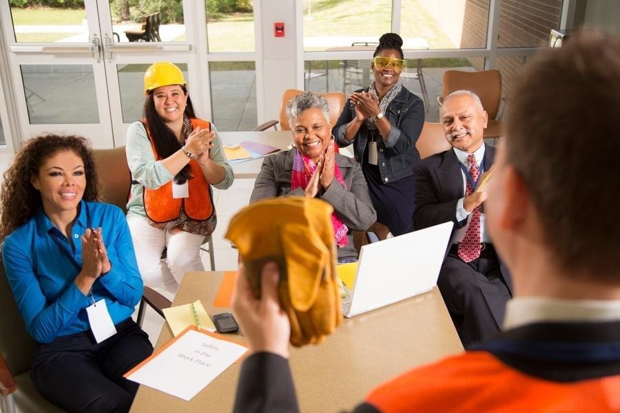 A group of working construction workers clapping at a meeting.