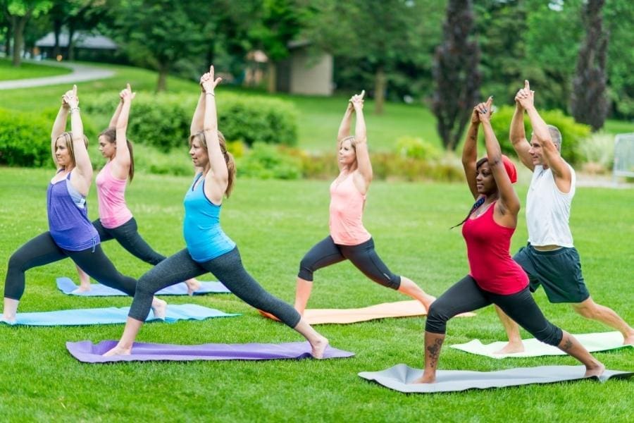 A group of people practicing yoga in a park, embracing work-life balance.