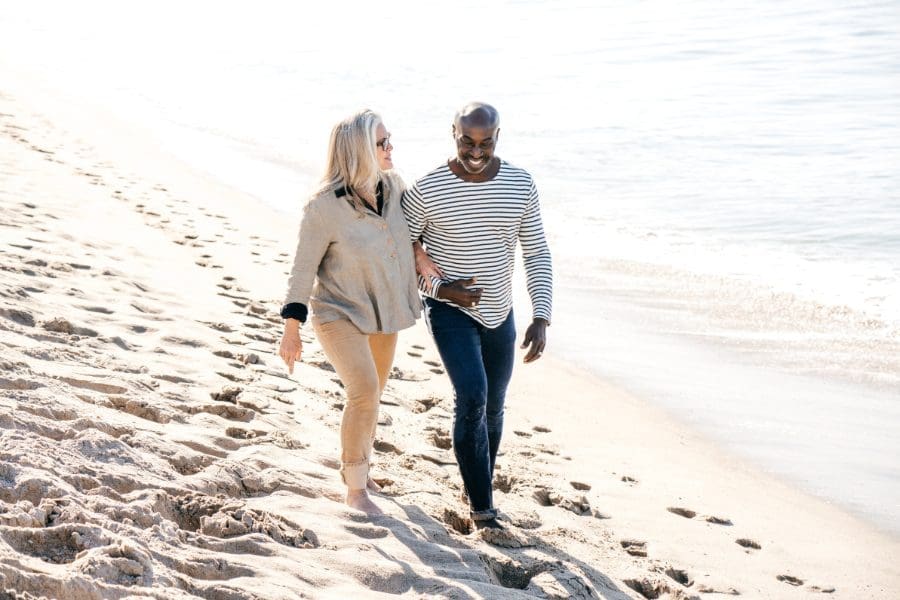 An older couple walking along the beach, supplemented by senior health insurance policies.