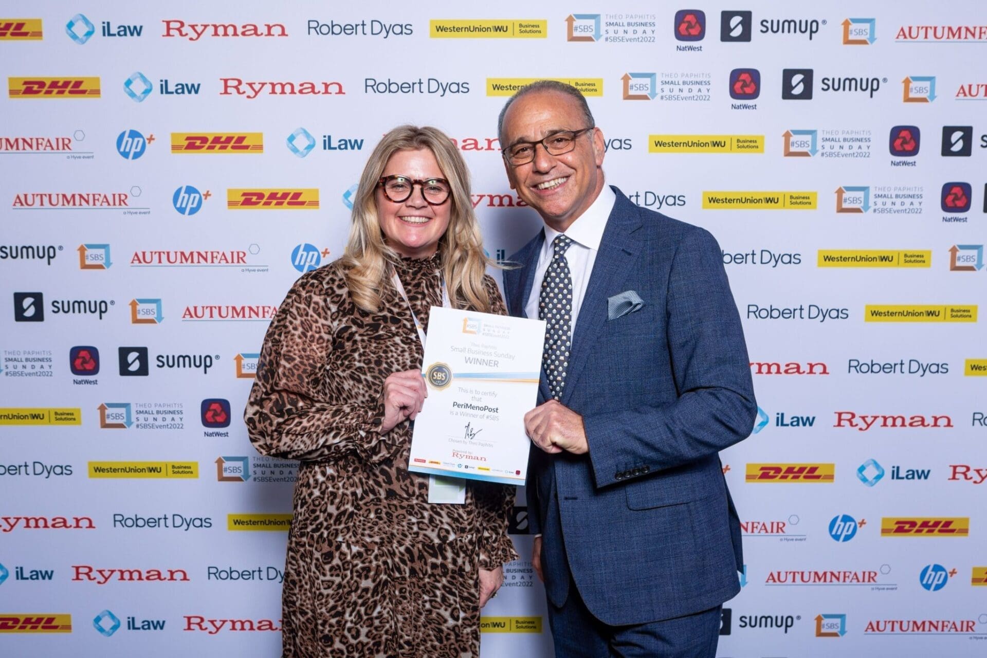 A woman undergoing a drastic career change poses with an award with Theo Pathitis