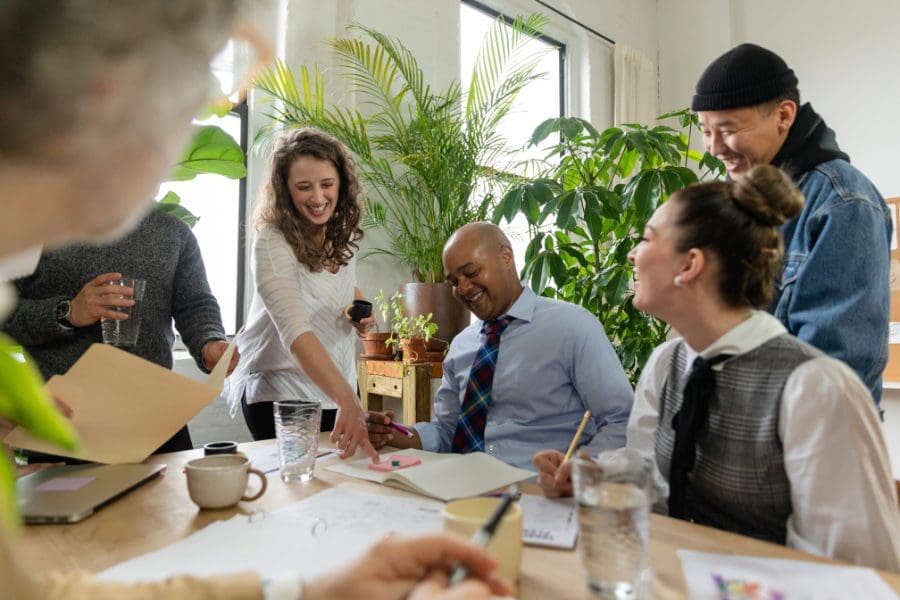 A group of people sitting around a table, strategizing their employee wellbeing.
