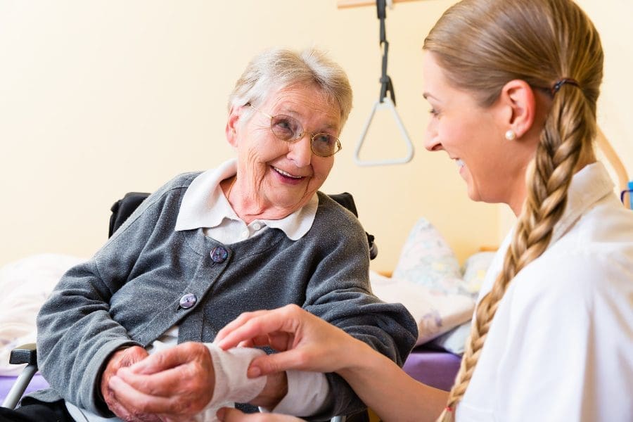 A nurse is providing health and social care to an elderly woman in a wheelchair.