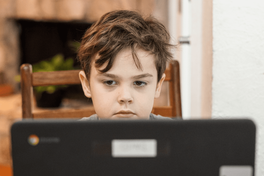 A young boy utilizing a laptop computer while practicing online safety.