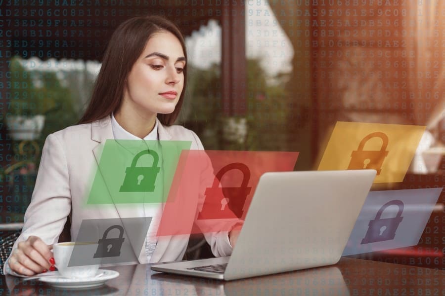 A woman sitting at a table with a laptop and padlocks on it, contemplating her career move into cyber security.