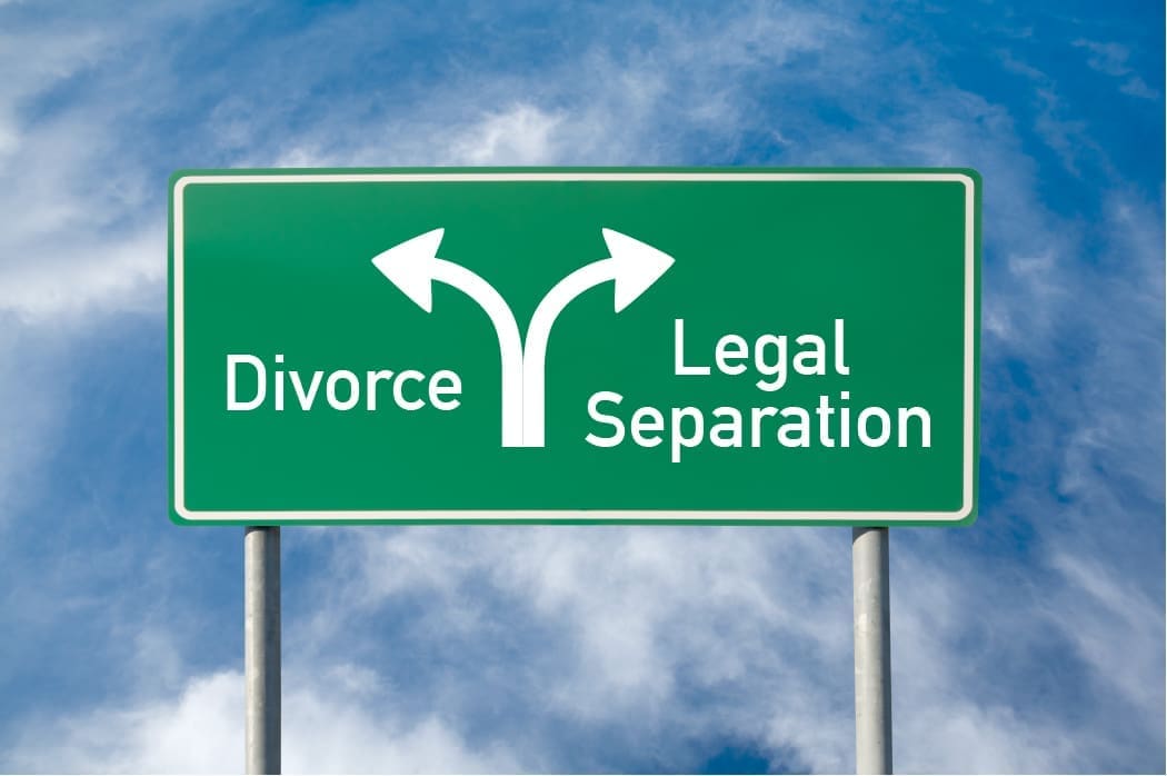 Green road sign with white arrows pointing left to "Divorce" and right to "Legal Separation" against a cloudy blue sky background.