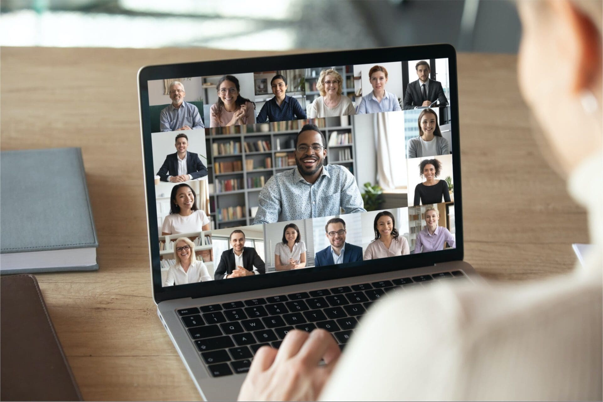 Person participates in a video conference on a laptop with multiple people displayed in a grid on the screen.